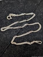 Close-up of the sterling silver chain link bracelet laid out on a dark surface, showing the spring ring clasp and chain details clearly.