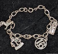 Sterling silver charm bracelet with dog, trophy, number '16', and golf bag charms on black background.