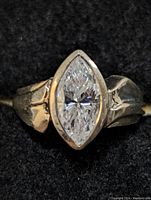 Close-up of top view of sterling silver ring with marquise-cut cubic zirconia stone set in bezel setting, showing the ring band and stone in detail.