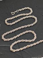 Photo of single sterling silver rope chain necklace laid flat showing chain pattern and clasp.