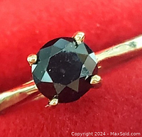 Close-up of round faceted black diamond in 4-prong setting