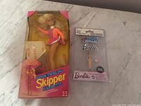 Wide shot showing both the Baton Twirling Skipper doll in original box and Barbie-themed toy baton still sealed in packaging.
