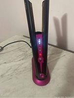Hair straightener upright in charging dock powered on with display lit