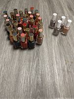 Multiple bottles of nail polish including Revlon and Essie arranged on the floor showing variety of colors.