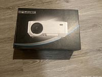 Black box of PrimeCables projector with image of projector on top