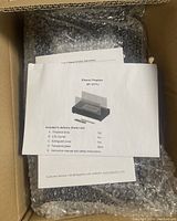 Inside box view showing components list and documentation on top of bubble wrapped fireplace body.