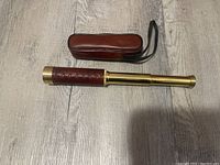 Telescope extended on floor with leather case above.