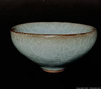 Side view of the tea bowl showing crackled celadon glaze with rim wear and rounded shape.