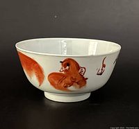 Side view of porcelain bowl showing iron red painted lions on white background.