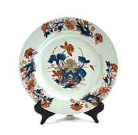 Front view of the porcelain plate on stand showing central lotus and foliate border.