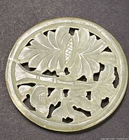 Top view of round translucent jade pendant showing reticulated floral carving detail.