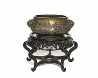 Front and side view of the carved bronze incense burner on an ornate wooden stand; stand not included in the lot.