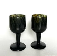 Front view of two dark green jadeite wine cups showing polished surface and rich color variation.