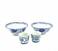 Front view of two blue and white porcelain bowls with floral and decorative patterns alongside two matching cups.