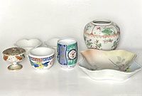 Front view of seven Japanese porcelain items arranged on a white surface.