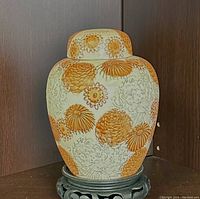 Front angled view showing the jar's shape and chrysanthemum floral pattern in orange and cream.