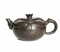 Front-view of teapot showing ribbon drape design and bud finial lid