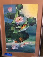 Photo of colorful print showing koi fish and lotus flowers with detailed coloring and shading, mounted and framed.