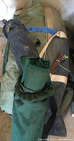 Lot contents showing rolled and packed green tent, dark folding camping chair, and folded green Go-Kot cot with carry bag