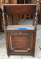 Full frontal view of the closed wooden book and magazine cabinet showing twisted legs, top open lift lid, and lower panel door.