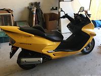 Side profile of yellow Reflex scooter showing body panels, seat and exhaust