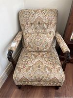 Front and side views of vintage arm chair showing patterned upholstery and carved wooden armrests