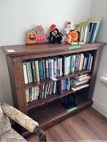 Front view of solid wood bookcase loaded with books and decorative items (contents not included)
