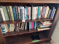 Bookshelves containing a variety of hardcover and paperback books including fiction, non-fiction and reference titles.