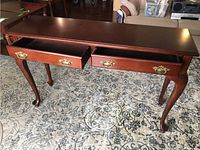 Front view of wooden console table showing two open drawers with brass handles and cabriole legs.