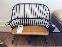 Front view showing spindle back, wide armrests with paint wear, and natural wooden bench seat with some surface marks.