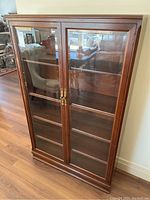 Front view showing full cabinet, glass doors, shelving, and base molding