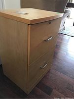 Side angle showing the filing cabinet with closed drawers and light wood finish.