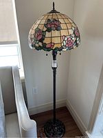Full view of floor lamp showing Tiffany style stained glass shade with pink rose motif and carved wood base, approximately 60 inches tall