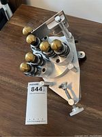 Top-down view of the multi-head cutter tool showing six brass-capped cutter heads on an aluminum triangular base.