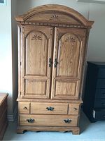 Front view of closed wardrobe showing arched top, carved detail and bottom drawers