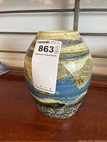 Side view of oval pottery vase showing fish carving and blue band design.