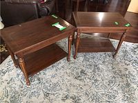 Two matching wooden side tables placed on a patterned rug showing overall shape and design.