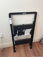 Full view of the folded metal step ladder showing two steps with peeling paint and a black finish frame.