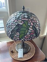 Lamp at an angle showing stained glass shade with floral pattern and metal base