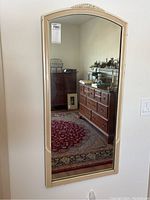 Full view of the antique framed wall mirror reflecting a room with furniture and carpet.
