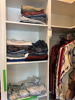 Closet shelves showing folded pants, jeans, and tops with various colors and patterns including denim, plaid, solid, and florals.