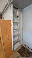 Full view of the 6 foot aluminum ladder leaning against wall near cabinet and door.
