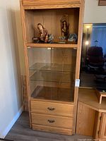Full view of one cabinet showing glass doors with two shelves and two wooden drawers below with metal handles.