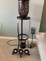 Photo showing a large floor candle holder with glass insert, tall wall-mounted candle holder, and small three-armed tea light holder