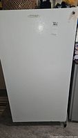Front view of upright freezer with door closed showing Frigidaire badge and sticker.