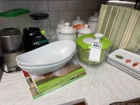 Photo showing the full lot with coffee grinder, blender, serving bowls, salad spinner, canisters, sushi plates and kitchen towels on countertop.