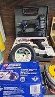Photo showing the MasterCraft pneumatic nailer in case, Campbell Hausfeld impact wrench packaging, and hand tools including a 6 inch plastic wheel.