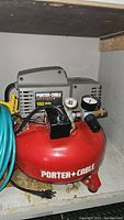 Red Porter-Cable Jetstream pancake air compressor with gray motor housing and pressure gauge, placed on a shelf.