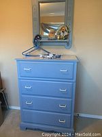 Full view of soft blue four-drawer cabinet with white handles, no visible damage, drawers closed.