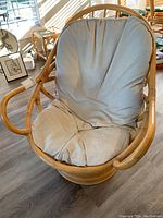 Front view of rattan rocking chair showing linen cushion and curved armrests.